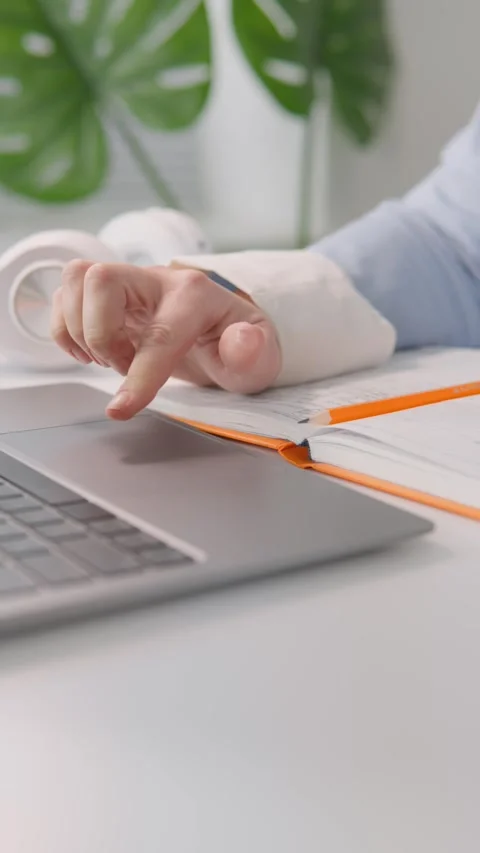 Closeup of a business professional using a laptop touchpad while referencing Stock Footage 340922118