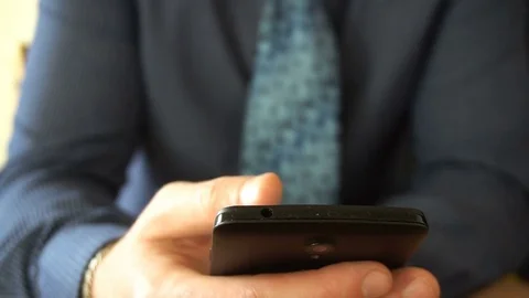 Closeup on a businessman browsing messages on his last generation smartphone. Stock Footage 76929580