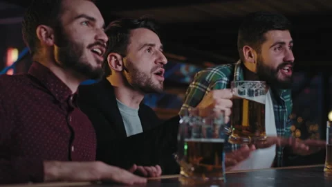 Closeup to the camera charismatic good looking guys in a pub watching a fav Stock Footage 134182965