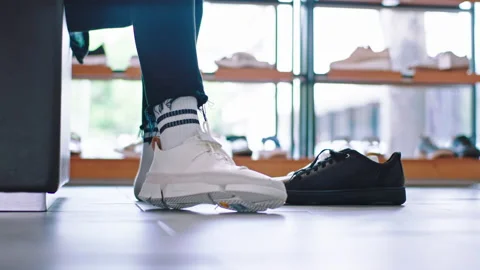 Closeup to the camera customer guy try a new pair of white shoes in a shoe shop Stock Footage 132192844