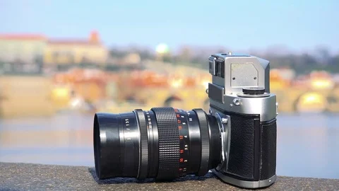Closeup on a camera on the edge of a stone bridge - a river and a townscape in Stock Footage 79429900