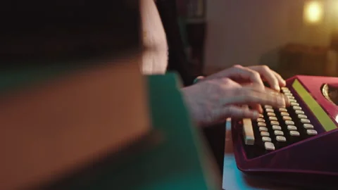 Closeup to the camera type some text on the typewriter man in a dark library Stock Footage 134063168