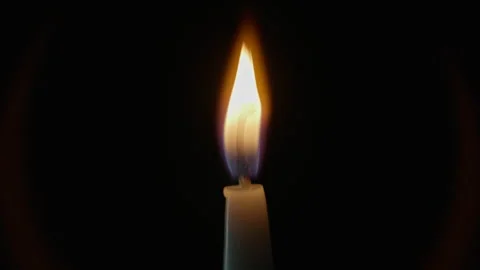 Closeup candle flame glowing atop wax standing tall on dark studio background Stock Footage 332506495