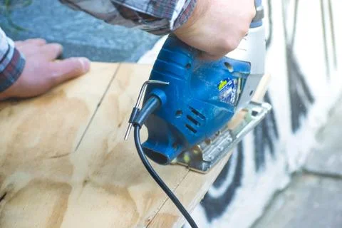 Closeup of Carpenter man using circular saw for cutting wooden board to build Stock Photos