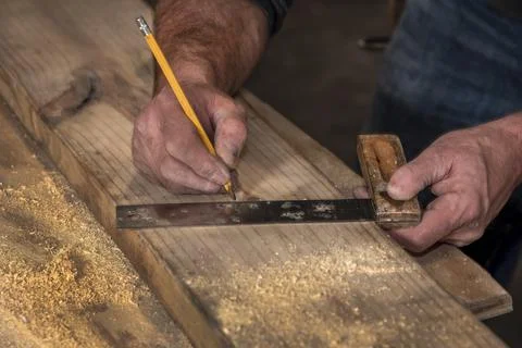 Closeup carpenter rough hands  marking wood board with old square 写真素材