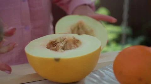 Closeup Caucasian Hands Halving Melon On Cutting Board, Seeds And Pulp Revealed Stock Footage 329405617
