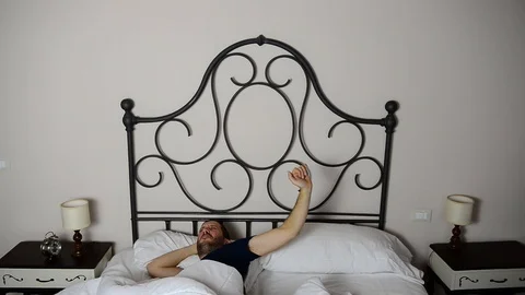 Closeup of caucasian man when he wakes up and stretches in bed 스톡 동영상 122305439