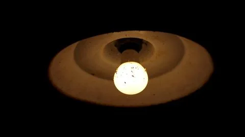 Closeup of a ceiling light shining with the lightbulb covered in dust and spider Stock Photos