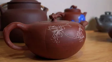 Closeup on a ceramic kettle on a shelf - more ceramic dishes in the blurry Video stock 85784925