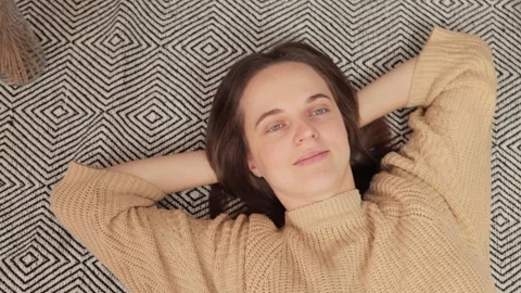 Closeup of cheerful young casually dressed woman laying on floor at home Stock Footage 259624043