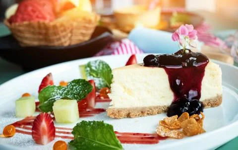 Closeup Cheese cake with raspberry topping in white dish,blurry lightaround Stock Photos
