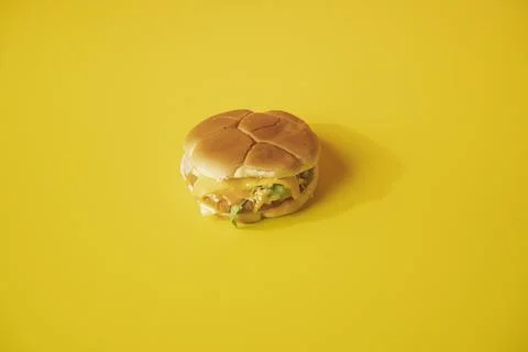 Closeup of a cheeseburger on a plain yellow background looking delicious and fre Stock Photos