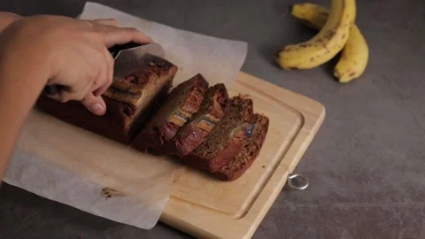 Closeup of chef cutting banana bread loaf on wooden cutting board Stock Footage 139260098