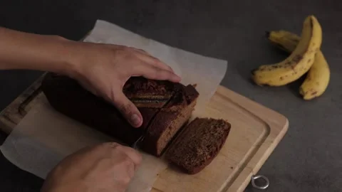Closeup of chef cutting banana bread loaf on wooden cutting board Stock Footage