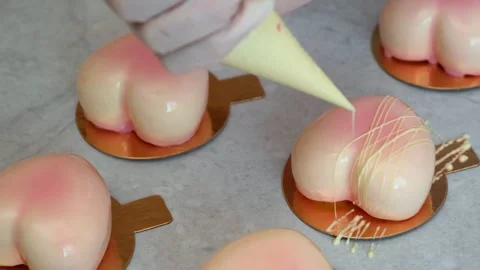 Closeup, chef decorates pastry bag with white glaze cakes in the form of a heart 库存影片 149033067