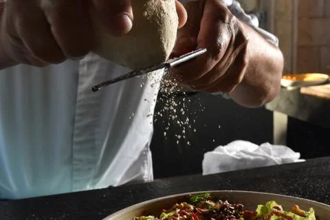 Closeup of chef grating parmesan cheese onto salad Stock Photos