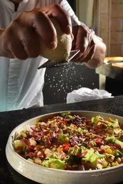 Closeup of chef grating parmesan cheese onto salad Stock Photos