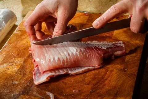 Closeup chef hands cut fish fillet by knife Stock Photos