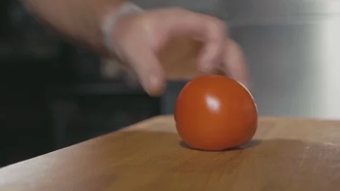 Closeup chef hands cutting slices of tomato on wood cutting board Stock Footage 80655365
