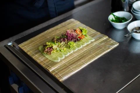 Closeup chef preparing salad with eel cucumbers and lettuce leaves on mat Stock Photos