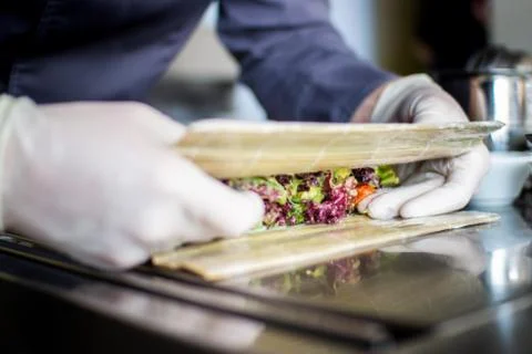 Closeup chef preparing salad with eel cucumbers and lettuce leaves on mat Stock Photos
