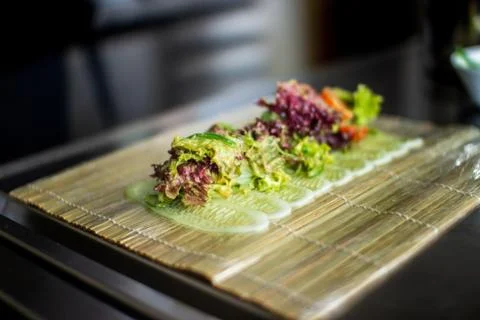 Closeup chef preparing salad with eel cucumbers and lettuce leaves on mat Stock Photos