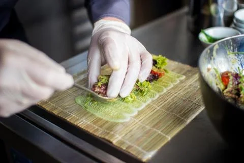 Closeup chef preparing salad with eel cucumbers and lettuce leaves on mat Stock Photos