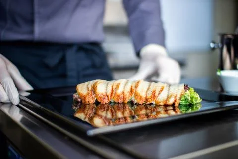Closeup chef preparing salad with eel cucumbers and lettuce leaves on mat Stock Photos
