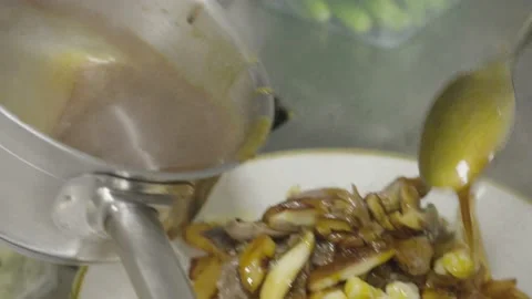 Closeup of a chef Putting gravy on poutine french fries with cheese curds on a p Stock Footage 237075339