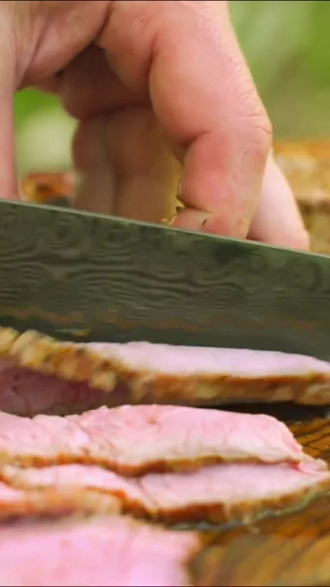 Closeup of a chef slicing perfectly cooked mediumrare roast beef Stock Footage 336656783