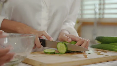 Closeup, the chef is using a knife to cut cucumbers in the kitchen. Stock Footage 202840587