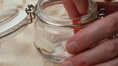 Closeup chefs puts pieces of sun dried tomatoes with seasonings in glass jar. Stock Footage 254270600
