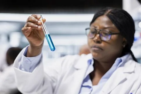 Closeup of chemical engineer in lab inspecting blue liquid clarity in test tube Stock Photos