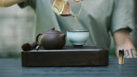 Closeup of Chinese tea being poured during mindful ceremony in natural backyard Video stock 312636222