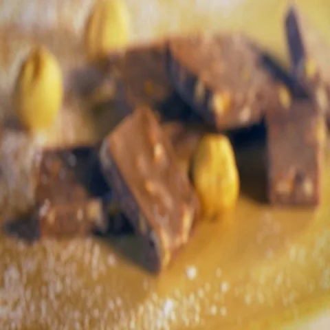 Closeup of chocolate blocks with hazelnuts and icing sugar on a wood table. Stock Footage 69574071