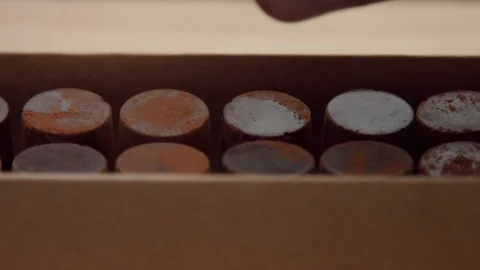 Closeup of chocolate candy box and a man's hand picked up one of it Stock Footage 86287270