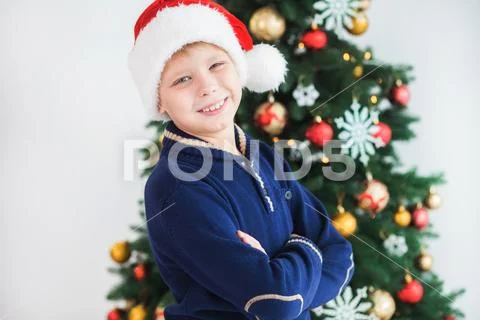 Closeup Christmas portrait of happy smiling young kid wearing red Santa hat Stock Photos