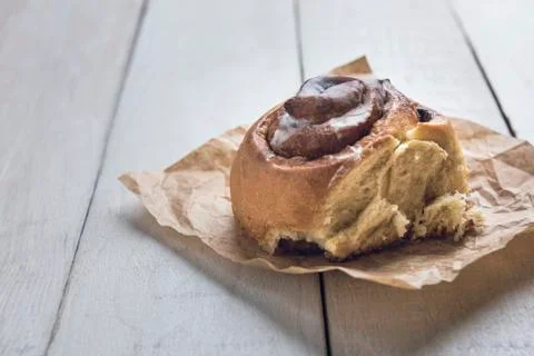 Closeup of a cinnamon roll over a white rustic wooden table. Stock Photos
