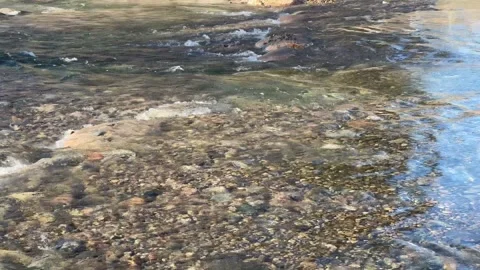 Closeup of clear river flowing across rocky rapids Video stock 273176579