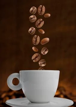 Closeup of coffee beans falling into coffee cup Stock Photos