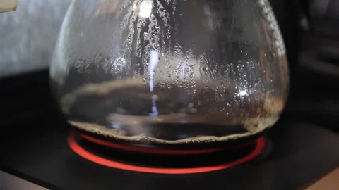 Closeup of coffee being brewed into a clear glass pot. A dripping stream ripples Stock Footage 121845314