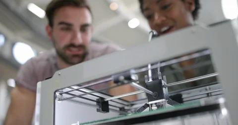 Closeup of colleagues looking at a 3D printer Stock Footage 86818292