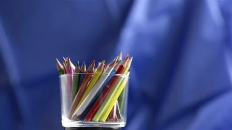Closeup of colored pencils rotating over blue background. Seamless looping Stock Footage 71574669