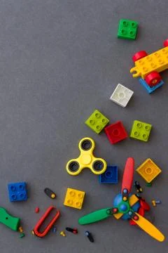 Closeup of colored plastic cubes and bright yellow spiner on gray background. Stock Photos