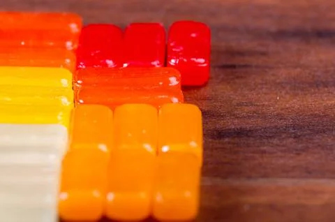 Closeup colorful rectangular hard candy lying on wooden surface 스톡 사진
