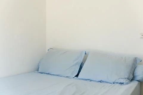 Closeup of a comfortable bed with light blue bedding and pillows against a .. Stock-Fotos