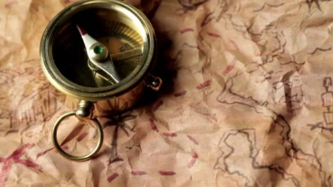 Closeup of compass over stained yellowed paper sheet with part of treasure ma Stock Footage 257870318
