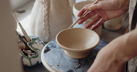 Closeup of concentrated young ceramist using scraper for shaping pottery Stock Footage 208074922