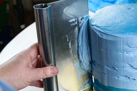 Closeup of a confectioner using a spatula on the side of the cake to spread t Stock Photos