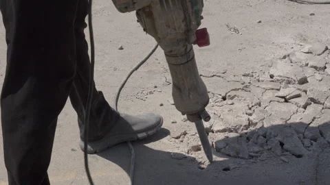 Closeup of construction worker operating jackhammer on cracked concrete pavement Stock Footage 343403631